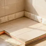 Coupe d'un sol carrelé montrant l'isolation sous carrelage avec un système de chauffage intégré, pour un confort optimal.