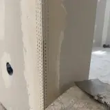 Angoli in cartongesso pronti per la stuccatura. Un angolo è rinforzato con nastro metallico, mentre l'altro è già parzialmente stuccato.
