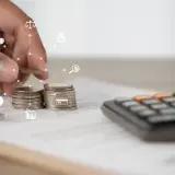Dłoń układa monety, obok kalkulator i dokumenty. Ikony symbolizują finanse i prawo, sugerując rozważania nad umową zlecenie a KRUS.