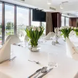 Elegancko nakryty stół z białymi tulipanami, idealny na uroczystość. Zastanawiasz się, ile trwa komunia w restauracji? To zależy od wielu czynników, ale zazwyczaj trwa kilka godzin.