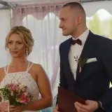 Iza i Kamil, ślub od pierwszego wejrzenia. Panna młoda z bukietem, pan młody w garniturze, patrzą na siebie z uśmiechem.
