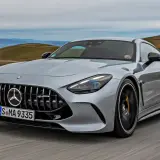 Srebrny Mercedes-AMG GT sunie po krętej drodze, ukazując swoją sportową sylwetkę i potężny grill.