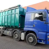 Blauer LKW mit großem grünen Container. Die Bedeutung eines solchen LKW ist der Transport von Schüttgut oder Abfall.