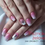 Dłonie z paznokciami w stylu ombre, z różowym gradientem i błyszczącymi serduszkami. Idealne uzupełnienie hybrydy.