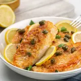 Délicieux poulet au citron, garni de câpres et de rondelles de citron frais, prêt à être dégusté.
