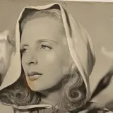 Portret Tamary Łempickiej w nakryciu głowy, z lokami opadającymi na ramiona.