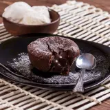 Un délicieux moelleux au chocolat, cœur coulant, saupoudré de sucre glace, servi avec de la glace à la vanille. Une recette gourmande à tester !