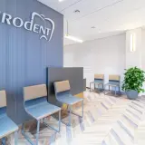 Nowoczesna poczekalnia gabinetu stomatologicznego z logo "Eurodent", krzesłami i rośliną.