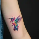 Koliber tattoo small, w akwarelowym stylu, z kolorowymi plamami farby.