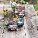 Romantische deko gartentisch mit Blumen und Kerzen in bunten Gläsern.