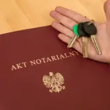 Dłoń z kluczami spoczywa na akcie notarialnym o majątku osobistym.