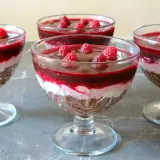 Pyszny deser z mascarpone i galaretką w pucharkach, udekorowany malinami. Idealny na letnie popołudnie.