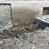 Prace przy podbijaniu fundamentów. Widoczny wykop i fragmenty muru.