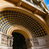 Dettaglio architettonico con decorazioni a squame dorate e blu, sculture di aquile e teste leonine. Un esempio di architettura del quartiere Coppedè.