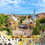 Kolorowa mozaika wita podczas zwiedzania Parku Güell. W tle bajkowe domki i panorama Barcelony.
