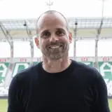 Uśmiechnięty trener Radomiaka na tle stadionu.