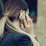 Kobieta z blond kucykiem rozmawia przez telefon, planując urlop na żądanie.