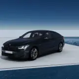 Eleganckie bmw g32 w ciemnym kolorze prezentuje się na platformie nad wodą, z błękitnym niebem w tle.