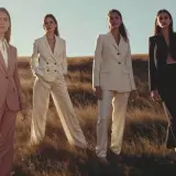 Quatre femmes en tailleurs élégants, dont un en lin textile, posent dans un champ d'herbes hautes au coucher du soleil.