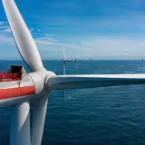 Wielka turbina wiatrowa na morzu, część projektu Baltica 2, z pracownikami na platformie. W tle widać kolejne morskie farmy wiatrowe.