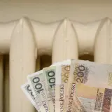 Pieniądze w ręku na tle grzejnika. Czy to zapowiedź bonu energetycznego 2026?