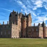 Castillo escocés con torres cónicas y un gran césped verde, perfecto para tus viajes a Escocia.