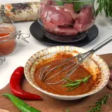 Przygotowanie marynaty do polędwiczki wieprzowej: miska z przyprawami, chili, czosnek i mięso w tle.