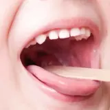 Bocca di bambino aperta con linguetta di legno per controllare la gola. Informazioni sulla faringite bambini quanto dura.