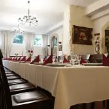 Długi stół w restauracji, nakryty białym obrusem, z czerwonymi serwetkami i kieliszkami. Czy rezerwacja stolika w restauracji jest płatna?