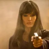 Angelina Jolie w filmach akcji, celująca z pistoletu.