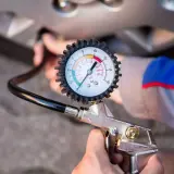 Manómetro de presión de neumáticos conectado a la válvula de una rueda. Aprende como saber la presion de las ruedas del coche para mayor seguridad.