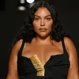 Modelo curvy con cabello oscuro y piel bronceada, luce un vestido negro con escote pronunciado y detalle de estampado de serpiente.