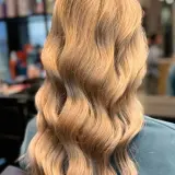 Lśniące, falowane blond włosy po zabiegu z użyciem olejków do włosów. Efekt zdrowych i nawilżonych pasm.