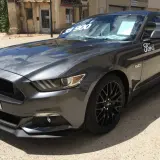 Szary Ford Mustang GT 5.0 z ceną 38 900 na szybie, gotowy do jazdy.