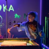 Chłopiec maluje farbami fluorescencyjnymi w ciemni. Niezapomniane urodziny dziecka w Szczecinie.