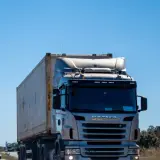 Ciężarówka Scania przewozi kontener. Zastanawiasz się, ile za kilometr busem po Polsce?