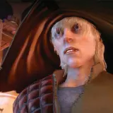 Cole z Dragon Age w swoim charakterystycznym stroju, z blond włosami i niebieskimi oczami, spogląda w górę.
