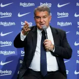 Joan Laporta, prezydent FC Barcelona, przemawia na tle logo klubu. Jego słowa kształtują przyszłość drużyny i jej trenerów.