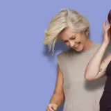 Två kvinnor med tuffa korta frisyrer ler mot kameran. Den ena har blont hår och den andra brunt.