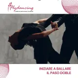 Two dancers in black outfits perform a dramatic Paso Doble pose against a grey backdrop.