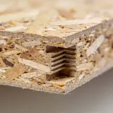 Gros plan sur un panneau OSB avec une rainure et un languette, montrant le sens de pose pour un assemblage solide.