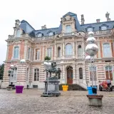 Devant un château, des sphères argentées, comme des habits de lumière, scintillent sur des structures métalliques, entourant une statue équestre.