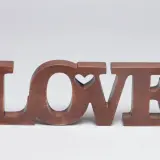 Letras de madera marrón forman la palabra "LOVE", con un corazón tallado en la "O".