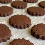 Deliziosi biscotti senza burro al cacao, con bordo ondulato, pronti per essere gustati.