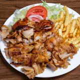 Talerz z kurczakiem gyros, frytkami, sałatą, pomidorem i cebulą.