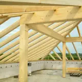 Solidne drewno na więźbę dachową, tworzące konstrukcję dachu nad budynkiem w stanie surowym.