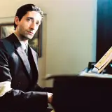 Adrien Brody gra na pianinie w filmie "Pianista", jednym z filmów Polańskiego alfabetycznie. Na ramieniu ma opaskę z gwiazdą Dawida.