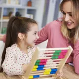 Mutter und Kind üben mit einem Abakus. Ein fröhlicher Moment vor der Einschulung, der den ersten Mathe-Test spielerisch vorbereitet.