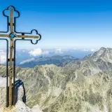 Krzyż na szczycie Gerlach bez przewodnika. Majestatyczne Tatry rozciągają się pod błękitnym niebem.