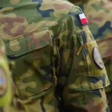 Żołnierz RP w mundurze moro, z naszywką z polską flagą. Dumnie reprezentuje kraj.